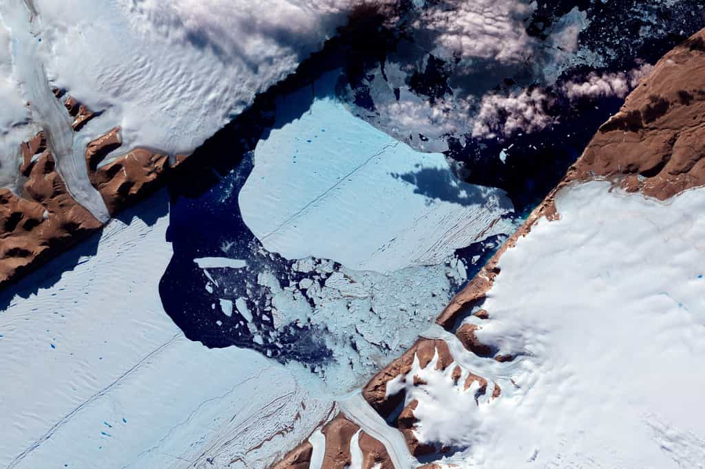 Le Groenland a connu un échauffement élevé au mois de juin, surtout dans sa partie sud, supérieur à la moyenne mondiale. Depuis plusieurs années, la circulation atmosphérique dans cette région est assez inhabituelle et se traduit par un faible apport d'humidité, donc de neige Cette image, obtenue le 21 juillet 2012 par l'instrument Aster (Advanced Spaceborne Thermal Emission and Reflection Radiometer) du satellite Terra, de la Nasa, montre un bloc de 32 km2 se détachant de la langue de banquise constituant l'extrémité du glacier d'eau douce Petermann. © Nasa Earth Observatory (image)/Jesse Allen/Robert Simmon/Données : Nasa/GSFC/Meti/Ersdac/Jaros et U.S./Japan Aster Science Team