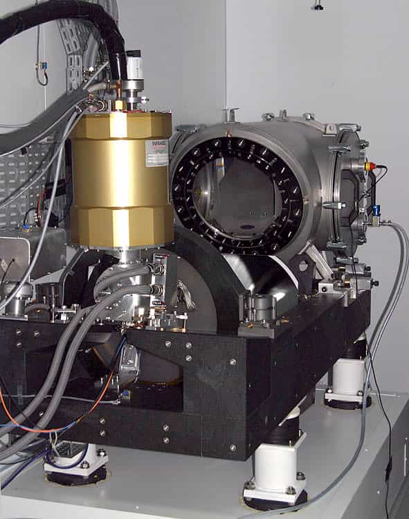 Le spectrographe Sophie, sur ses quatre pieds anti-vibrations. Il reçoit la lumière du télescope par quatre fibres optiques (grises, en haut à gauche). La lumière est envoyée à travers le hublot (une lame de Schmidt, au centre). © OAMP