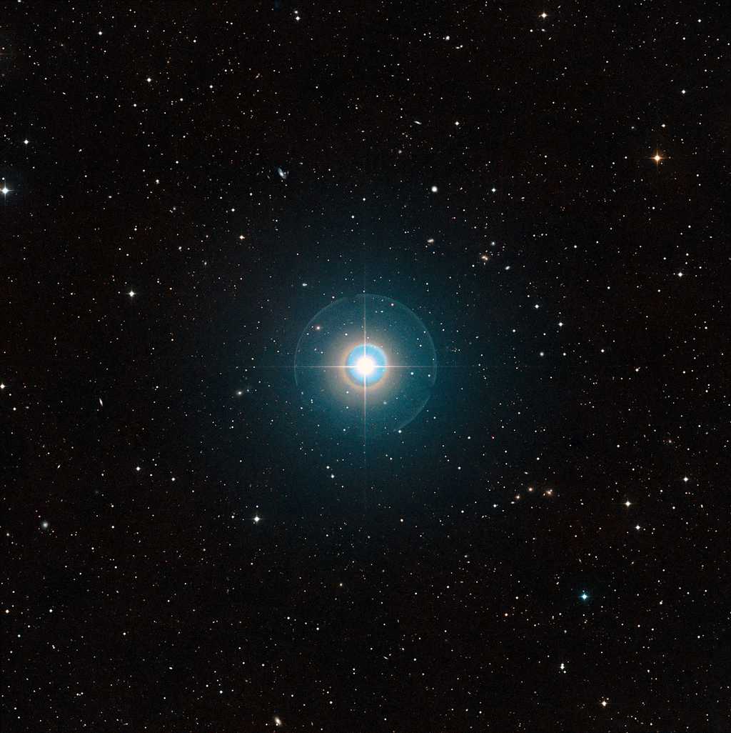 Cette image à grand champ du ciel autour de Tau Bootis a été créée à partir de clichés du Digitized Sky Survey 2. L'étoile elle-même, suffisamment brillante pour être vue à l'œil nu, se trouve au centre. Les traits fins et les cercles colorés autour d'elle sont des artefacts provoqués par le télescope et la plaque photographique utilisée et ne sont pas réels. L'exoplanète Tau Bootis b est en orbite à faible distance de l'étoile et est totalement invisible sur cette image. La planète vient juste d'être détectée de manière directe grâce à sa propre lumière en utilisant le VLT de l'ESO. © ESO/Digitized Sky Survey 2