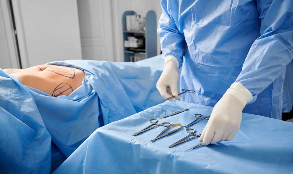 Chirurgien en gants stériles préparant des instruments médicaux, prêt à intervenir sur un patient. © Anatoliy_gleb, Adobe Stock