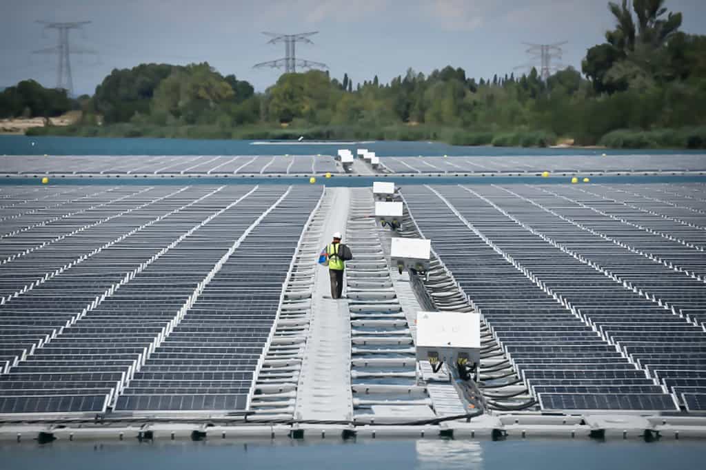 Un technicien marche entre les panneaux photovoltaïque de la centrale flottante O'Megal, le 30 juillet 2019 à Piolenc, dans le Vaucluse. © Gérard Julien, AFP