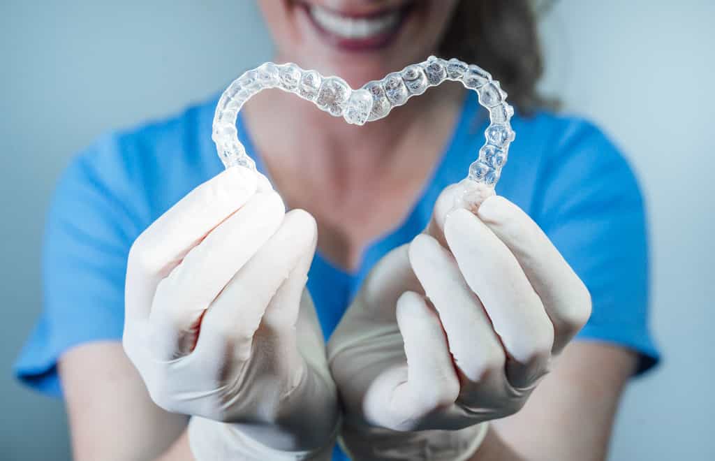 Les gouttières transparentes comme celles proposées par Invisalign sont très populaires chez les adultes souhaitant corriger l'alignement de leurs dents. © Karrastock, Adobe Stock