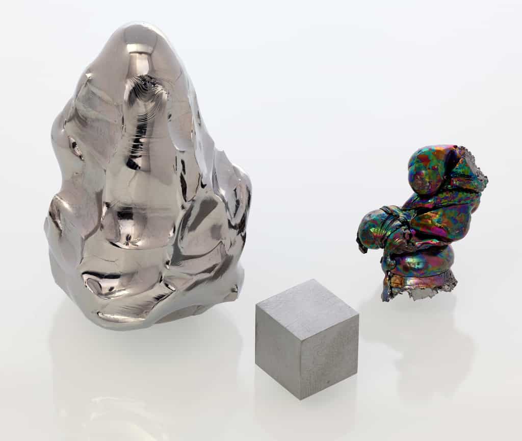 À gauche, la pointe fondue d'une électrode sacrificielle d'hafnium pur à 99,98 %. À droite, un lingot refondu d'hafnium oxydé (la couleur est un phénomène d'optique provoqué par une mince couche d'oxyde). Devant, un cube de 1 cm3 d'hafnium. © Alchemist-hp, Wikimedia Commons, CC by-nc-nd 3.0