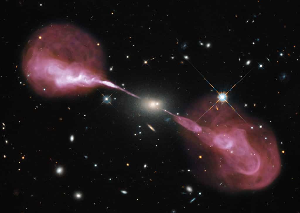 Hercules A est une galaxie elliptique située à environ 2 milliards d'années-lumière de la Voie lactée. Environ 1.000 fois plus massive que notre Galaxie, elle abrite un trou noir central de 2,5 milliards de masses solaires. On la voit dans le visible sur cette photographie prise par Hubble et sur laquelle a été surimposée une image réalisée dans le domaine des ondes radio par le VLA. Se révèlent alors deux lobes radio produits par des jets de matière relativistes, longs de plusieurs millions d’années-lumière. © Nasa, ESA, S. Baum and C. O'Dea (RIT), R. Perley and W. Cotton (NRAO/AUI/NSF), and the Hubble Heritage Team (STScI/AURA)