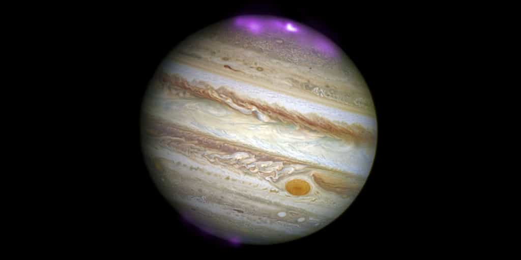 Cette illustration montre le disque de Jupiter, observé avec le HST en lumière visible et les aurores polaires en rayons x, observées avec Chandra, affichées en fausse couleurs violettes. L'émission plus intense (hot spot) au Nord apparait comme une tache plus blanche au centre de l'aurore. © rayons X : Nasa/CXC/UCL/W.Dunn et al., visible : Nasa/STScI.