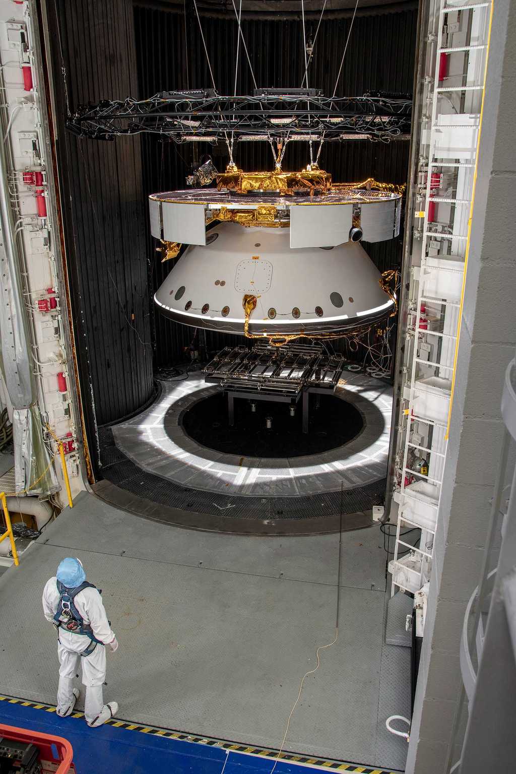 Un ingénieur du Jet Propulsion Laboratory (JPL) inspecte la sonde spatiale de la mission Mars 2020 qui patiente ici dans une chambre de simulation spatiale le 9 mai 2019, en attendant d'y être testée. © NASA JPL/CalTech.