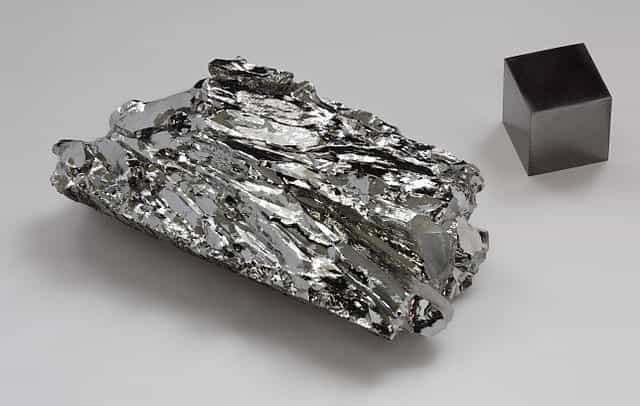 Le molybdène est notamment utilisé pour durcir les aciers. Ici, un fragment de molybdène cristallin ainsi qu'un cube d'1 cm3. © Alchemist-hp, Wikimedia Commons, CC by-nc-nd 3.0