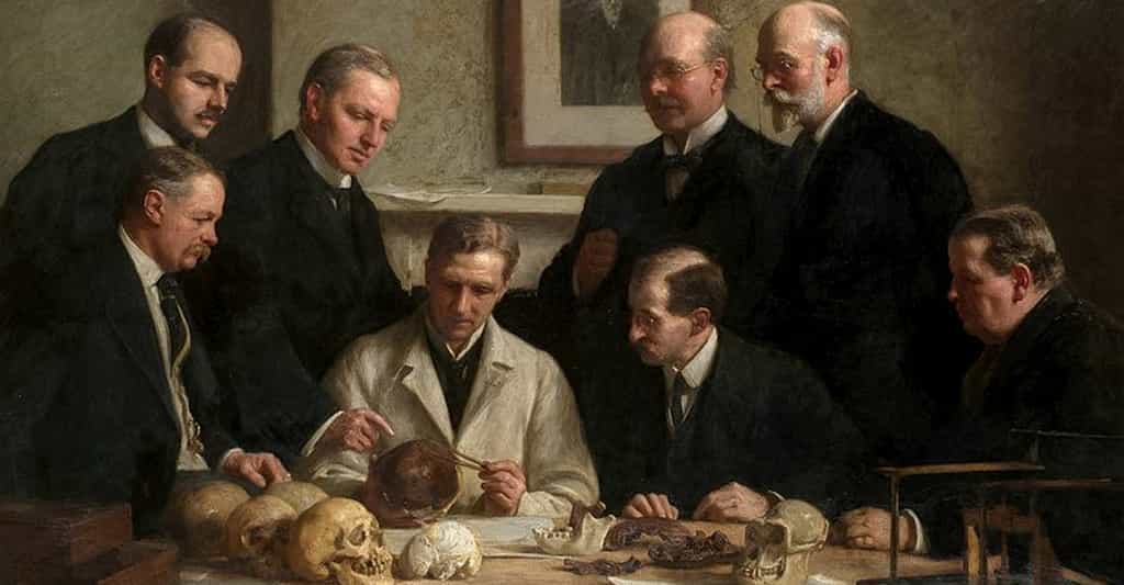 En 1915, le peintre John Cooke immortalise la découverte du crâne de Piltdown dans ce tableau où des scientifiques l'examinent avec attention. Charles Dawson et Sir Arthur Smith Woodward sont représentés, debout, à droite. © DP