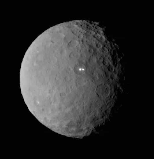 Dawn était à environ 46.000 km de sa destination, la planète naine Cérès, le 19 février lorsque sa caméra a pris cette image. Le point blanc remarqué depuis son approche, il y a quelques semaines, apparait double à l’intérieur d’un cratère. © Nasa, JPL-Caltech, Ucla, MPS, DLR, IDA