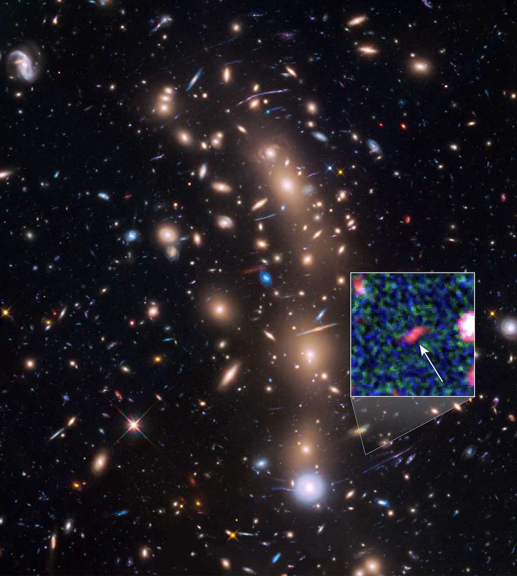 L’amas de galaxies MACS J0416.1-2403 à l’avant-plan permet de magnifier les objets du champ profond. Grâce à cet effet de lentille gravitationnelle, une équipe a débusqué une vingtaine de protogalaxies dont une, sombre et petite (ici 20 fois plus brillante grâce à l’amas), qui existait déjà lorsque l’univers n'avait que 400 millions d’années (son décalage vers le rouge est d'environ 10). Les astronomes l’ont surnommée « Tayna », « premier-né » en langue aymara. © Nasa, Esa, L. Infante (Pontificia Universidad Católica de Chile)