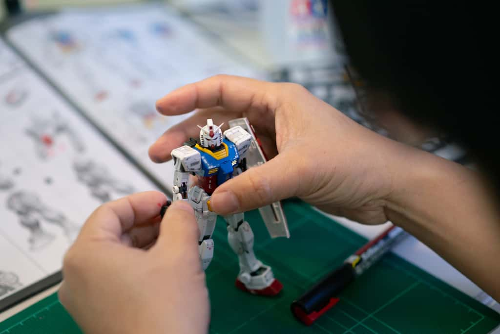 Un collectionneur construit minutieusement une figurine Gundam. © Lalalululala, Adobe Stock