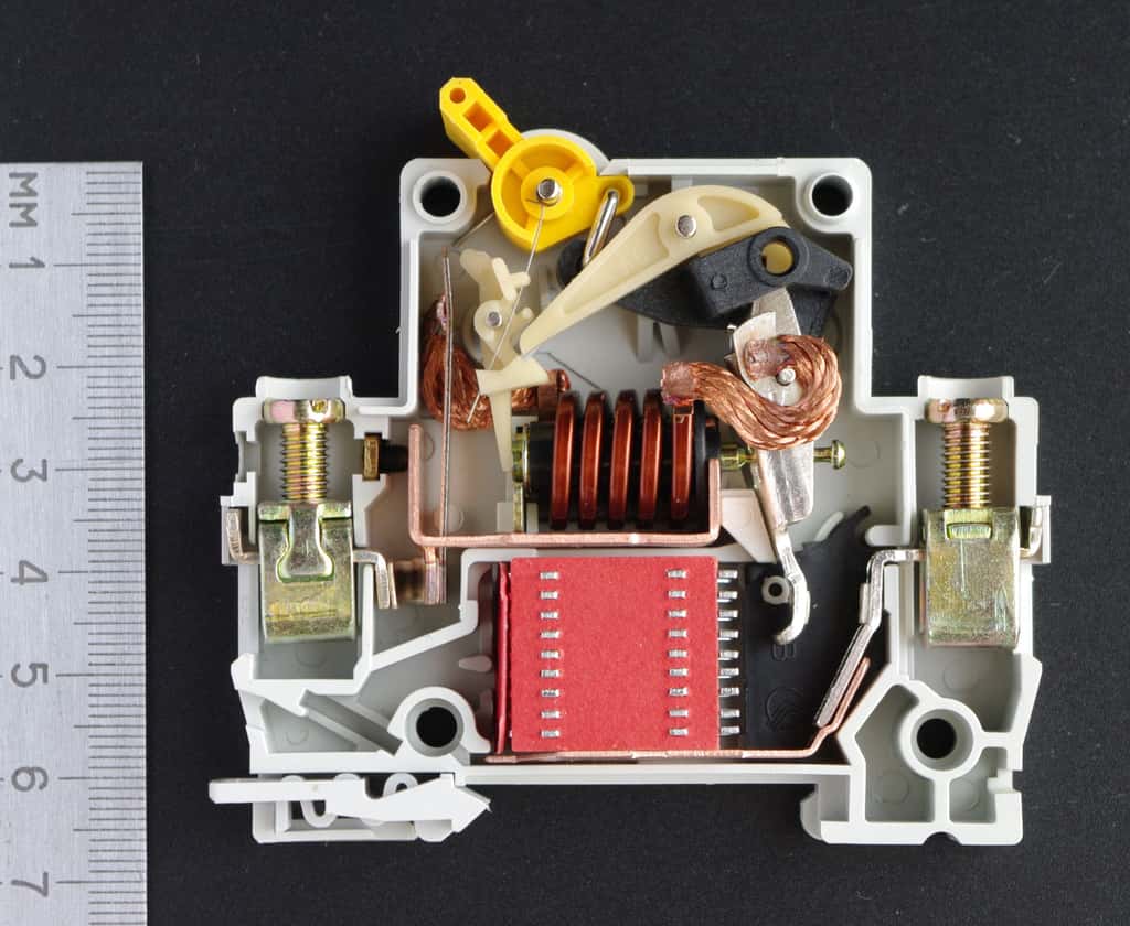 Sur cette image de disjoncteur magnétothermique, on distingue la bilame de la partie thermique (sur lequel est accroché la tresse en cuivre) et la bobine de la partie magnétique. © CC By rezemika