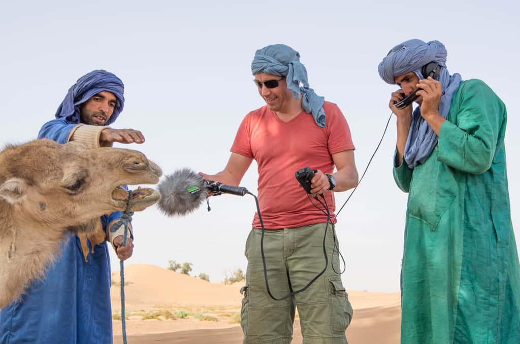 Stéphane Pigeon capturant le blatèrement d'un chameau dans le désert du Sahara. De gauche à droite : le chameau, Larsen (le conducteur de caravane), Stéphane, Youssef (le guide). © Stéphane Pigeon