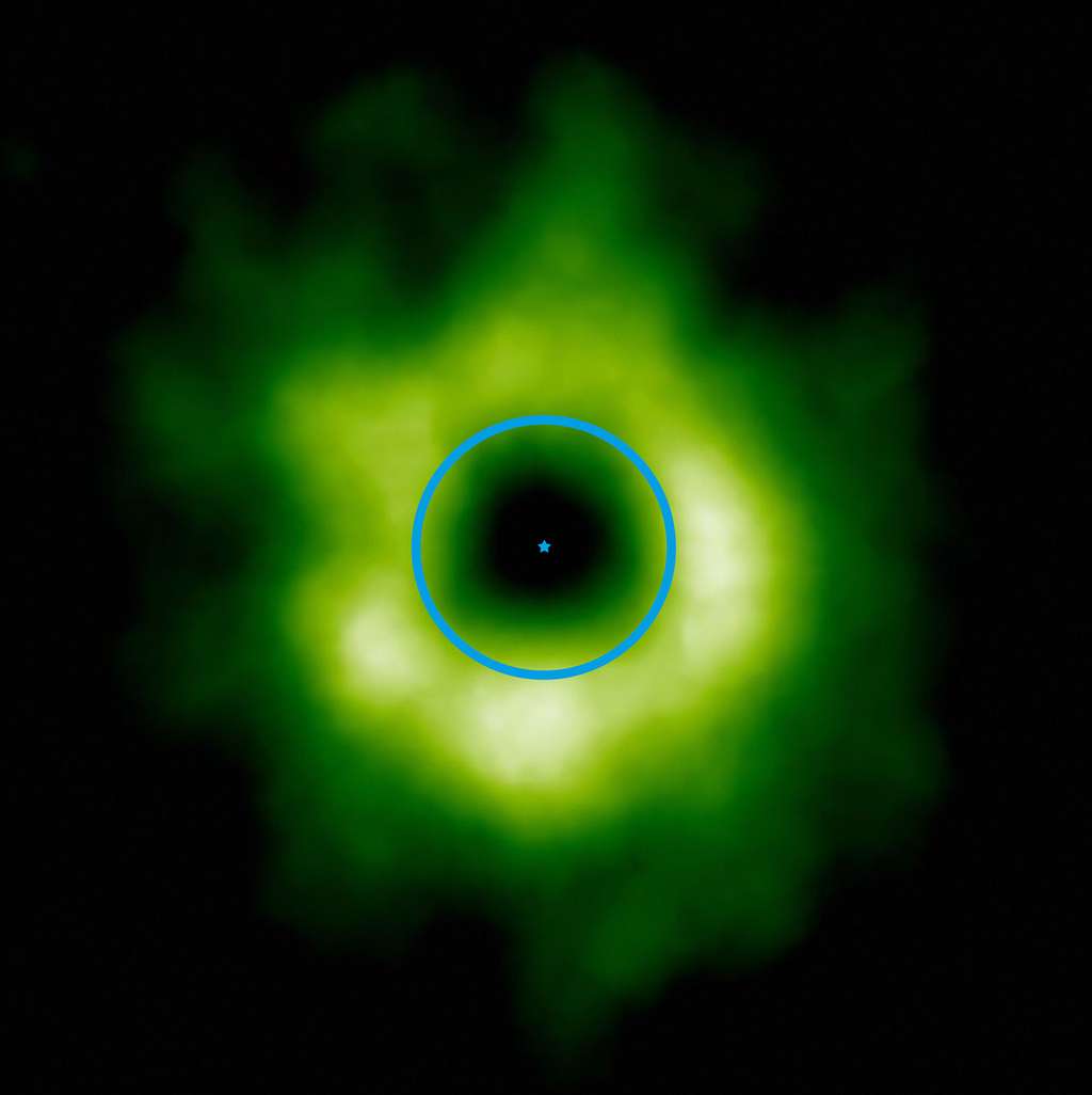Cette image prise par Alma montre en fausses couleurs (teintes vertes) la région où le monoxyde de carbone est présent à l’état de glace autour de l’étoile TW Hydrae (indiqué au centre). À titre d’échelle, le cercle bleu symbolise l'orbite de Neptune autour du Soleil. La transition vers la glace de monoxyde de carbone pourrait aussi marquer la limite intérieure de la zone où se forment les petits corps glacés, tels que les comètes et les planètes naines comme Pluton et Éris. © ESO