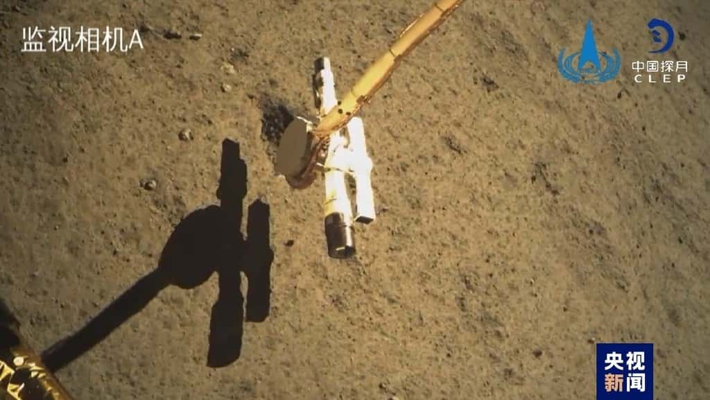 Cette image prise par une caméra embarquée montre le bras robotique de l'atterrisseur en train de collecter des échantillons du sol. C'est la première fois que l'on récolte des échantillons de la face cachée ! ©  CNSA, Clep