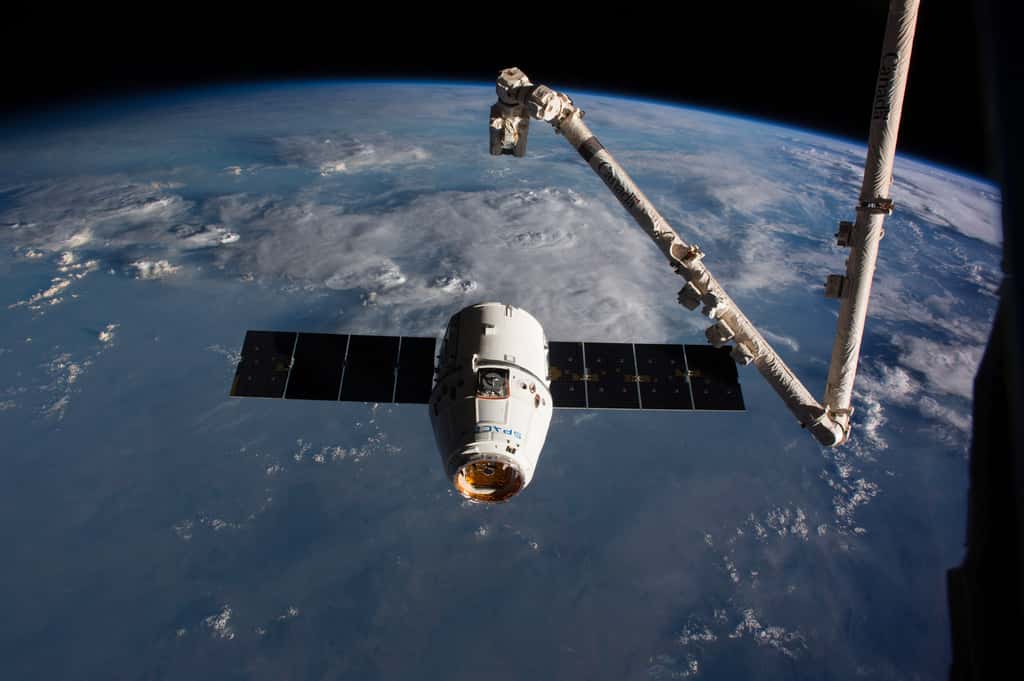 Une capsule Dragon s'apprête à se faire saisir par le bras robotique de la Station pour l'amarrer au complexe orbital. © Nasa