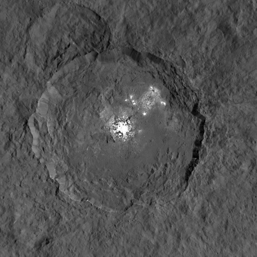 Une des vues les plus détaillées du cratère Occator (90 km de diamètre), prises par la sonde Dawn, où figure l’ensemble de taches brillantes le plus remarquable de Cérès. Des panaches ont été observés lorsque la région est exposée au Soleil. © Nasa, JPL-Caltech, UCLA, MPS, DLR, IDA