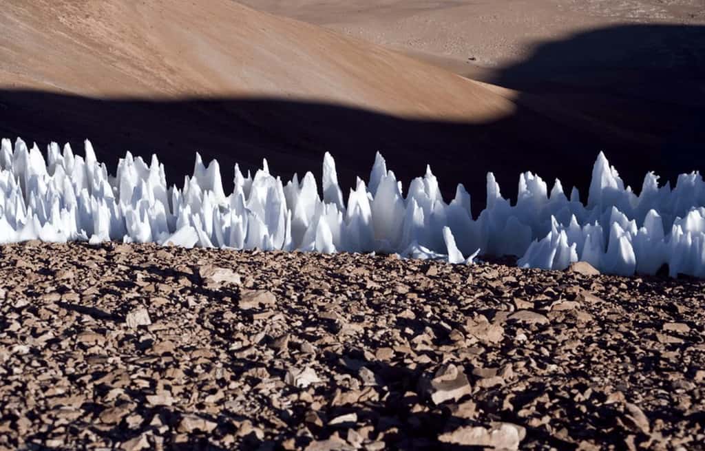 Sur Terre, on observe des pénitents aux latitudes tropicales et subtropicales, comme par exemple ici dans les Andes, au Chili. Les pénitents se forment d’autant mieux que les rayons du Soleil frappent à la verticale, touchant les creux dans la neige ou la glace plutôt que les parois. Ici, la sublimation a creusé la glace jusqu’à atteindre le sol rocheux. © ESO