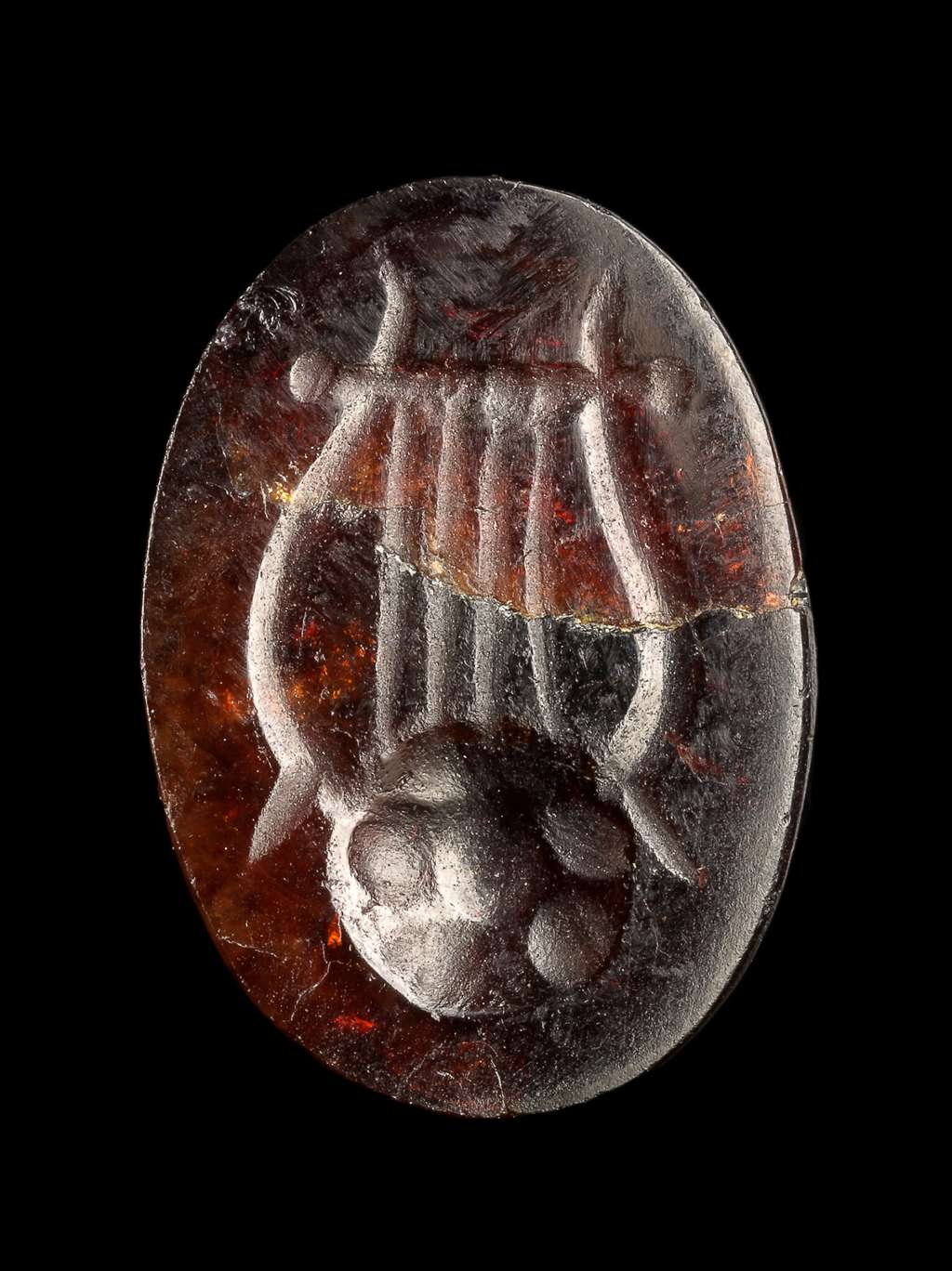 La gemme rouge gravée d'une lyre est plus petite qu'une phalange et fait partie des nombreux vestiges trouvés avec les épaves de navires. © Yaniv Berman, <em>Israel Antiquities Authority</em>