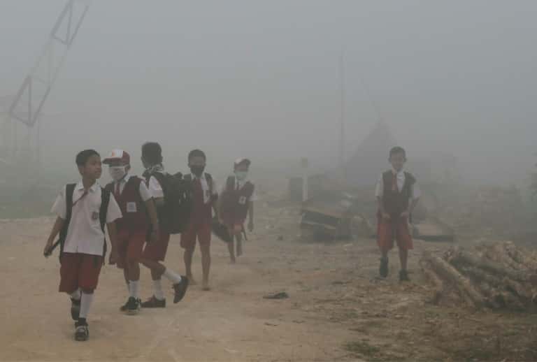 Des enfants indonésiens marchent vers leur école dans l'air pollué par de gigantesques incendies de forêt à Palembang, dans l'île de Sumatra, en octobre 2019. © Abdul Qodir, AFP 