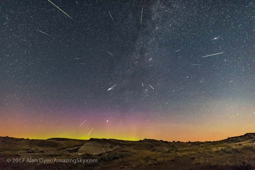 Photo composite prise dans la nuit du 12 au 13 août 2017 dans le <em>Dinosaur Provincial Park</em>, en Alberta au Canada. Le radiant des Perséides est bien visible, en direction de Persée et de la Voie lactée. En haut à droite, on aperçoit le disque laiteux de la galaxie d’Andromède. En bas, à gauche, une délicate aurore boréale embrase l’horizon. © 2017 Alan Dyer, <a href="http://www.amazingsky.com/" title="Amazing sky" target="_blank">AmazingSky.com</a>