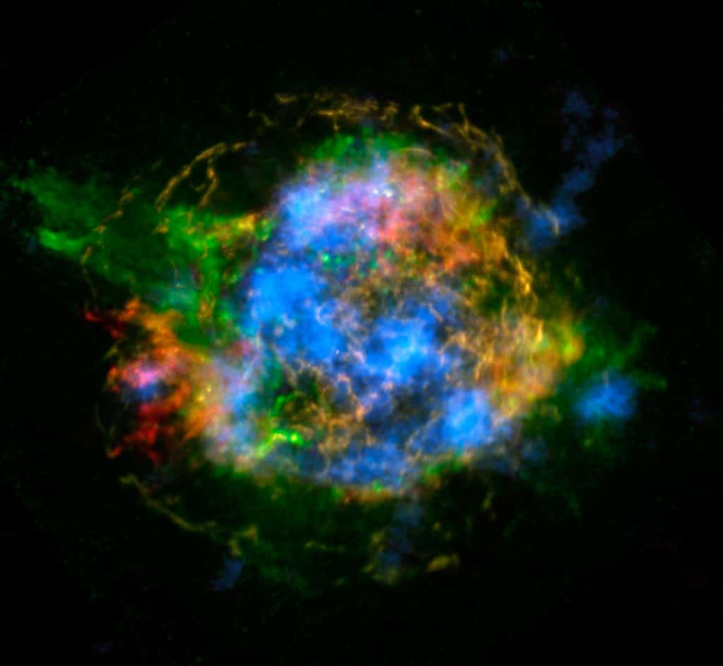 Les restes de la supernova à l'origine de Cassiopée A présentent des aspects différents quand on les observe en cherchant des traces bien spécifiques des émissions dans le domaine des rayons X de certains éléments. Ici, en rouge, les émissions des atomes de fer et, en vert, celles du silicium et du magnésium chauffés par l'explosion de la supernova. En bleu, ce sont les émissions des noyaux de titane 44 radioactifs. Ils proviennent sans ambiguïté du cœur de l'étoile avant son explosion. © <em>Lawrence Livermore National Laboratory</em>