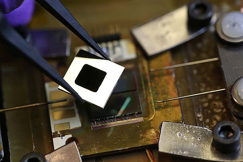 Au centre du carré blanc se trouve l’équipement nanostructuré qui a été développé au MIT pour absorber toute l’énergie du spectre solaire, afin de la convertir en chaleur puis en rayonnement thermique. Le récepteur se compose de nanotubes de carbone, tandis que l’émetteur intègre des cristaux photoniques omnidirectionnels Si/SiO<sub>2</sub>. En dessous se trouve une cellule photovoltaïque au silicium. © John Freidah