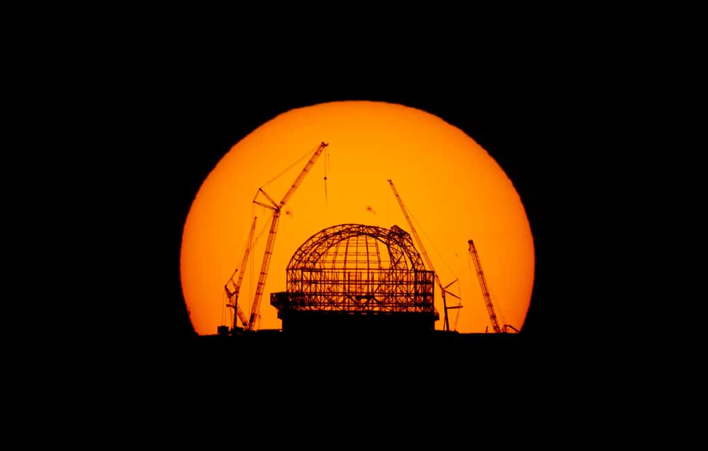 Superbe photo de l'ELT en construction devant le Soleil qui se lève, le 23 août 2023. On peut distinguer à la surface de ce dernier des taches sombres. © E. Garcés, ESO