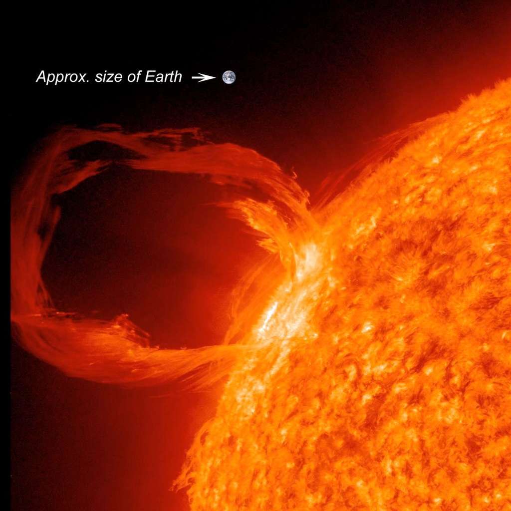 Saisie par le satellite SDO, une spectaculaire éruption solaire survenue en mars 2012. La Terre, représentée à côté de cette arche de matière ionisée, à peu près à la bonne échelle (<em>Approx. size of Earth</em>), donne la mesure de ces phénomènes. Leur ampleur rend nécessaire la mise au point de systèmes de prédiction en raison du risque qu'ils font peser sur bon nombre d'activités spatiales ou terrestres. © <em>SDO Science Team</em>, Nasa