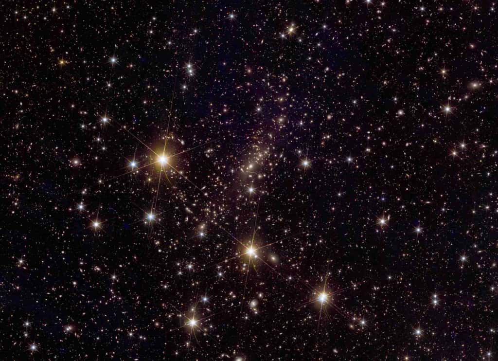 L’image d’Euclid de l’amas de galaxies Abell 2390 révèle environ 50 000 galaxies et montre un magnifique spectacle de lentilles gravitationnelles, représentant des arcs courbes géants dans le ciel – dont certains sont en réalité des vues multiples du même objet distant. Euclid utilisera l'effet de lentille (la lumière qui nous parvient depuis des galaxies lointaines est courbée et déformée par la gravité) comme technique clé pour explorer l'Univers sombre, mesurant indirectement la quantité et la répartition de la matière noire dans les amas de galaxies et ailleurs. Les scientifiques d'Euclid étudient également l'évolution de la masse et du nombre des amas de galaxies dans le ciel au fil du temps, révélant ainsi davantage d'informations sur l'histoire et l'évolution de l'Univers. Un zoom sur la vue d'Euclid d'Abell 2390 montrerait la lumière imprégnant l'amas provenant d'étoiles qui ont été arrachées à leurs galaxies mères et qui se trouvent dans l'espace intergalactique. L’observation de cette « lumière intra-amas » est une spécialité d’Euclid, et ces orphelines stellaires pourraient nous permettre de « voir » où se trouve la matière noire. © ESA/Euclid/Euclid Consortium/Nasa, traitement d'images par J.-C. Cuillandre (CEA Paris-Saclay), G. Anselmi ; Licence standard CC BY-SA 3.0 IGO ou ESA