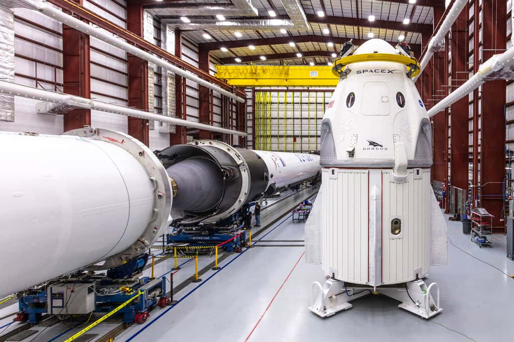 Le Crew Dragon et son lanceur, le Falcon 9 sont, ici, vus dans le bâtiment d'intégration de SpaceX du Centre spatial Kennedy de la Nasa. Les deux étages du Falcon 9 sont en position horizontale pour être assemblés ensemble. © Nasa, SpaceX