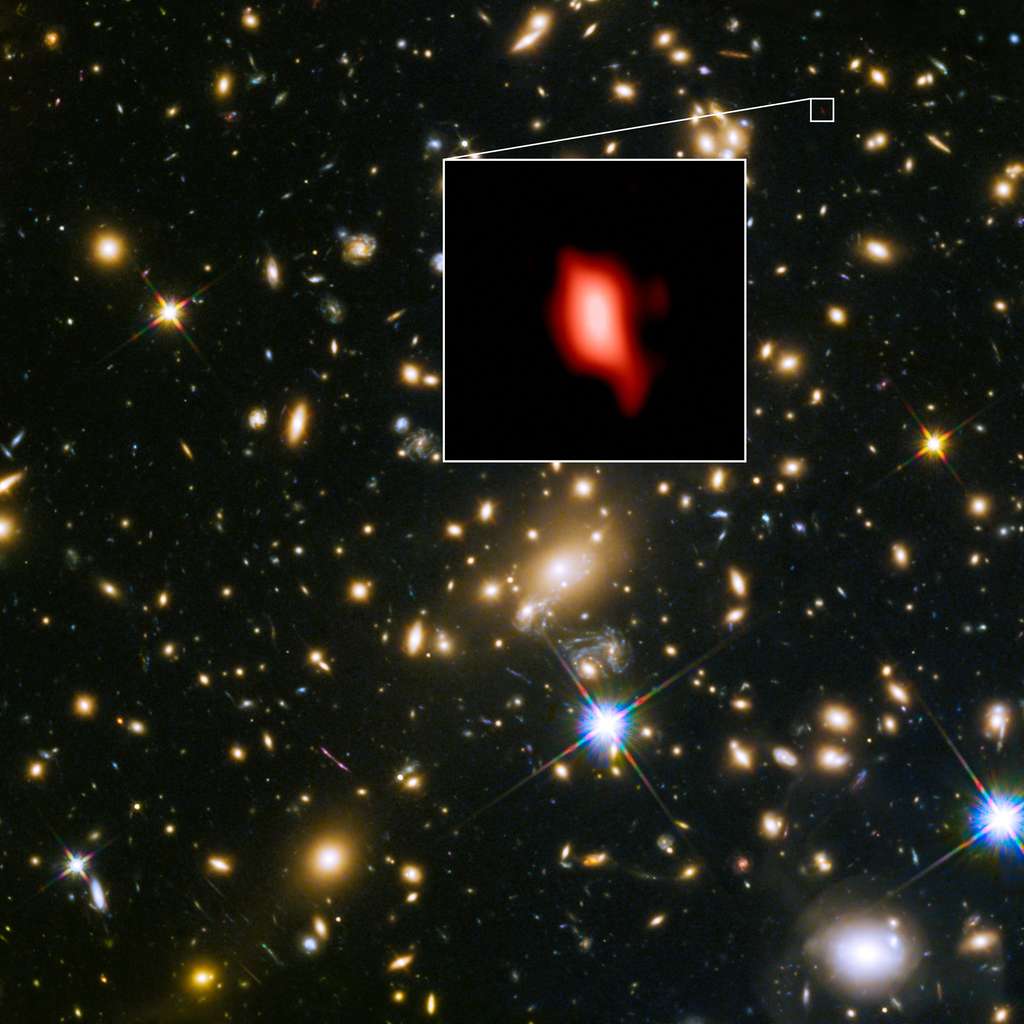 Cette image montre l'amas de galaxies MACS J1149.5+2223 pris avec le télescope spatial Hubble de la Nasa, ESA ; l'image en médaillon est la très lointaine galaxie MACS1149-JD1, vue telle qu'elle était il y a 13,3 milliards d'années et observée avec Alma. Ici, la distribution d'oxygène détectée avec Alma est représentée en rouge. © Alma (ESO/NAOJ/NRAO), Nasa/ESA Hubble Space Telescope, W. Zheng (JHU), M. Postman (STScI), the CLASH Team, Hashimoto et al.