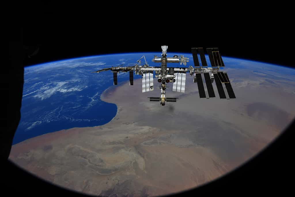 La Station spatiale internationale vue depuis l'hublot du véhicule Soyouz MS-18. On aperçoit clairement les panneaux solaires iRosa de dernière génération qu'ont notamment installés Thomas Pesquet et Shane Kimbrough. On peut aussi voir le bras robotique Canadarm-2, un Crew Dragon de SpaceX (tout en haut) et Nauka (tout en bas), le dernier module installé à l'ISS. © Roscosmos, P. Dubrov