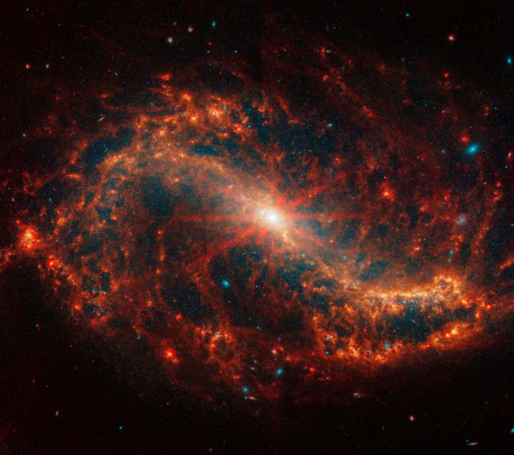 NGC 7496 se trouve à 24 millions d'années-lumière dans La Grue, une constellation de l'hémisphère austral. Le noyau central de l'image de Webb de la galaxie NGC 7496 commence par un point blanc brillant qui se fond en orange vif. Huit pointes de diffraction proéminentes émanent du centre. Un arc orange vif qui ressemble à un mince S vers l’arrière forme la barre et deux des bras de la galaxie spirale face à face. © Nasa, ESA, CSA, STScI, J. Lee (STScI), T. Williams (Oxford), équipe Phangs