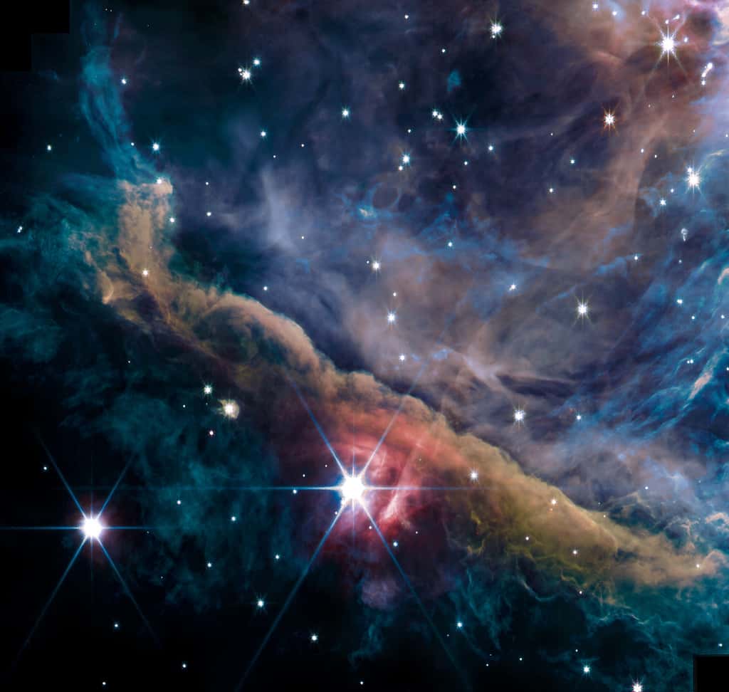 La « barre d'Orion » est un mur de gaz et de poussière à l'intérieur de la grande nébuleuse d'Orion, en cours de dislocation, à la fois sous le flot ultraviolet des jeunes étoiles du Trapèze (hors champ) et de θ<sup>2</sup> Orionis A, brillant devant (centre bas de l'image). Cette structure est une « région de photodissociation » pu PDR, dans le langage des astrophysiciens. © Nasa, ESA, CSA, PDRs4All ERS Team, Salomé Fuenmayor