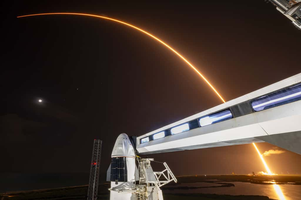 Décollage d'une Falcon 9 de SpaceX en arrière-plan du vaisseau Crew Dragon qui emmènera les passagers de Polaris Dawn. © SpaceX