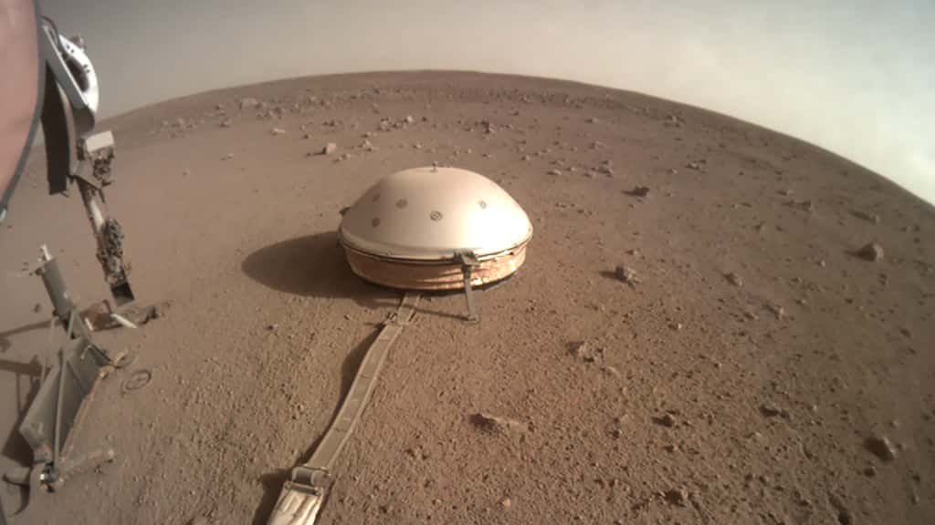 Le sismomètre Seis sur la surface de Mars. L'instrument est à l'abri sous son bouclier thermique et éolien. À gauche, on aperçoit l’instrument HP3 <em>(Heat Flow and Physical Properties Package)</em> qui n'est jamais parvenu à s'enfoncer dans le sol martien. © Nasa