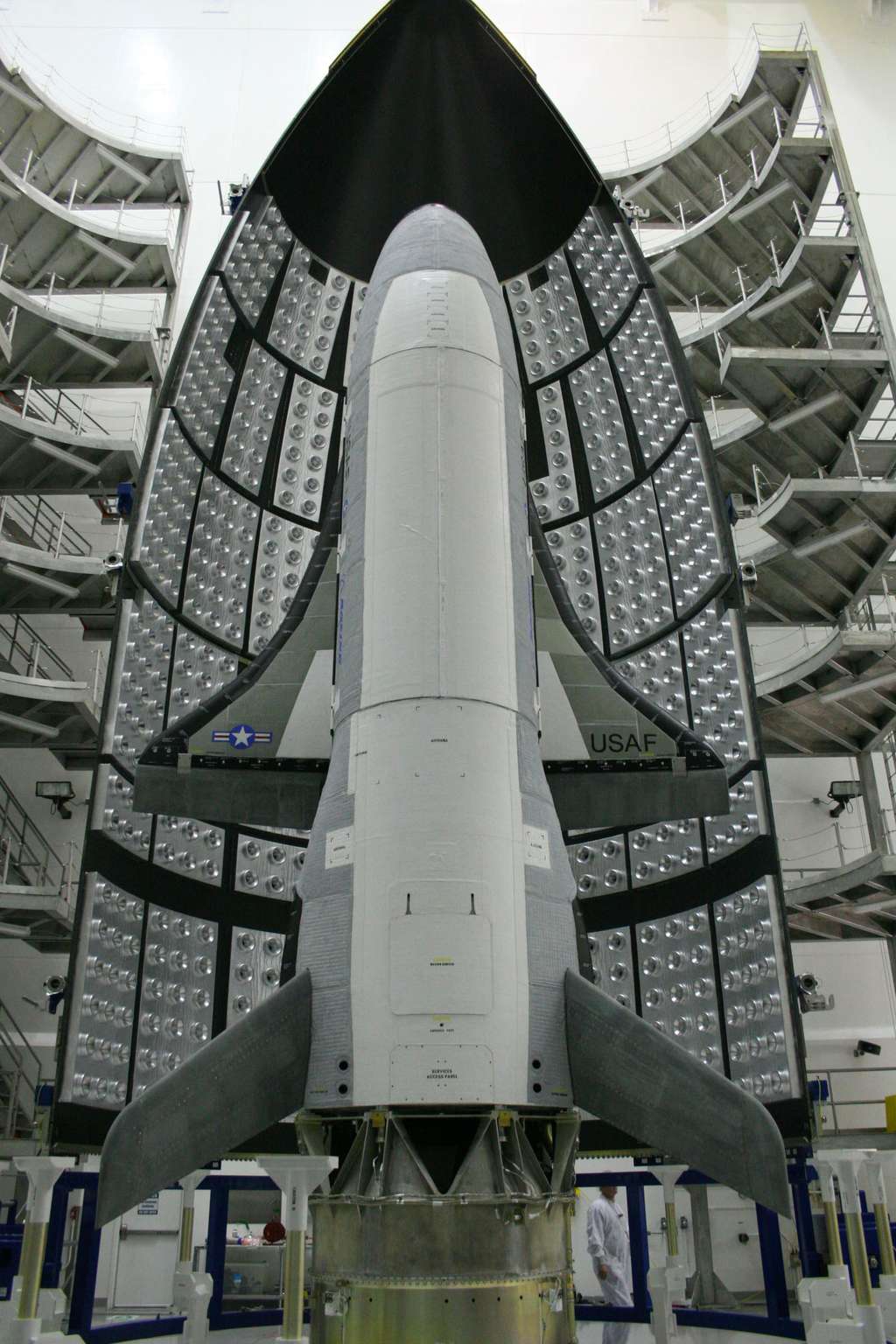 Un X-37B en cours d'intégration dans son lanceur. Il est vu devant une des deux demi-coiffes et installé au sommet du lanceur. © <em>U.S. Air Force</em>, Boeing