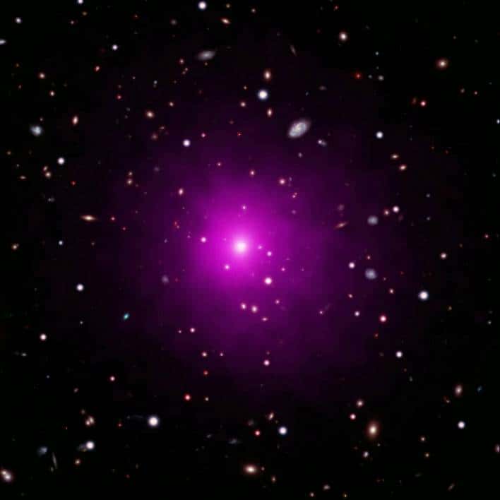 Un trou noir devrait se trouver dans l'énorme galaxie au centre de l'amas de galaxies Abell 2261, situé à environ 2,7 milliards d'années-lumière de la Voie lactée. Cette image composite d'Abell 2261 contient des données dans le visible, prise par Hubble et le télescope Subaru, montrant des galaxies dans l'amas en arrière-plan, et des données en rayons X de Chandra montrant des gaz chauds (de couleur rose) envahissant l'amas. Au centre de l'image, on voit la grande galaxie elliptique au centre de l'amas. © Nasa