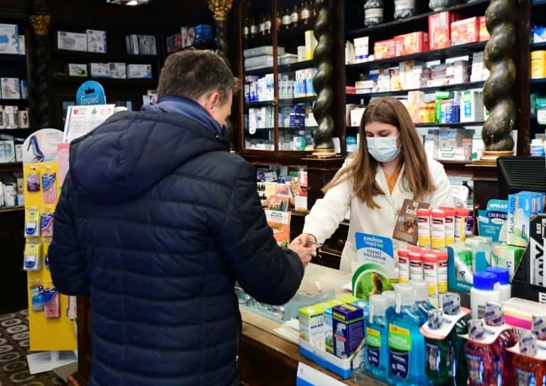 Une pharmacienne équipée d'un masque respiratoire sert un client le 22 février 2020 à Codogno, en Italie. © Miguel Medina, AFP