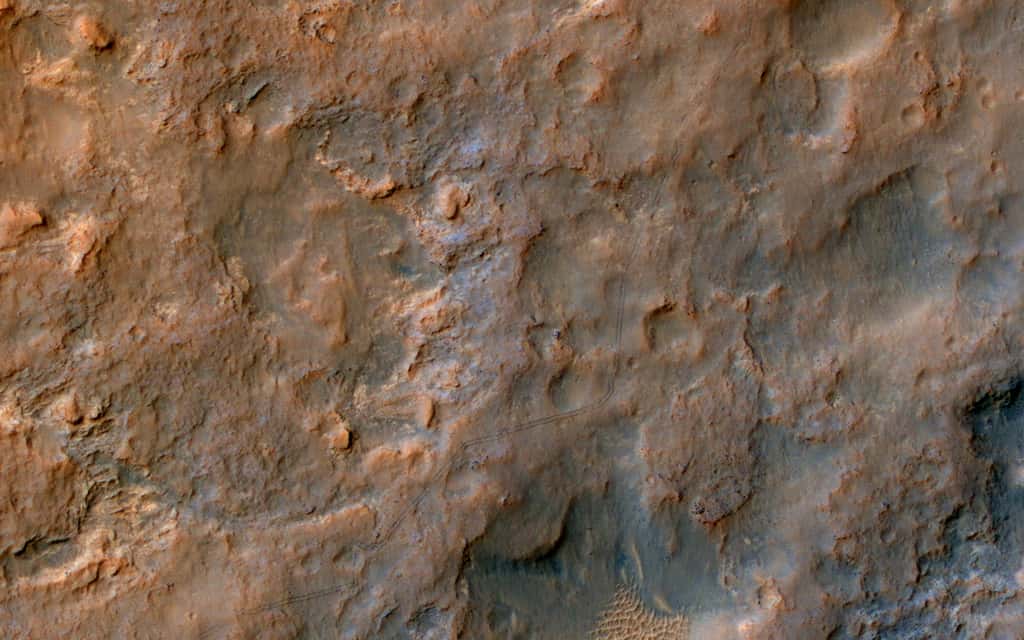 Sur cette photographie réalisée par la caméra HiRise de l'orbiteur MRO, on peut voir les traces laissées dans le sillage du rover Curiosity au cours de son périple qui le rapproche des flancs du mont Sharp. Cliquez sur l’image pour l’agrandir et observer les fines traces noires. © Nasa, JPL-Caltech