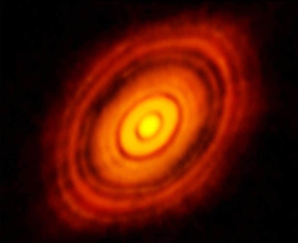Cette image, obtenue grâce au Grand réseau d’antennes millimétrique/submillimétrique de l’Atacama (Alma), montre le disque protoplanétaire entourant la jeune étoile <em>HL Tauri </em>et révèle des sous-structures à l’intérieur du disque qui n’avaient jamais été vues auparavant. Y compris les positions possibles des planètes se formant dans les taches sombres du système. © Alma, ESO