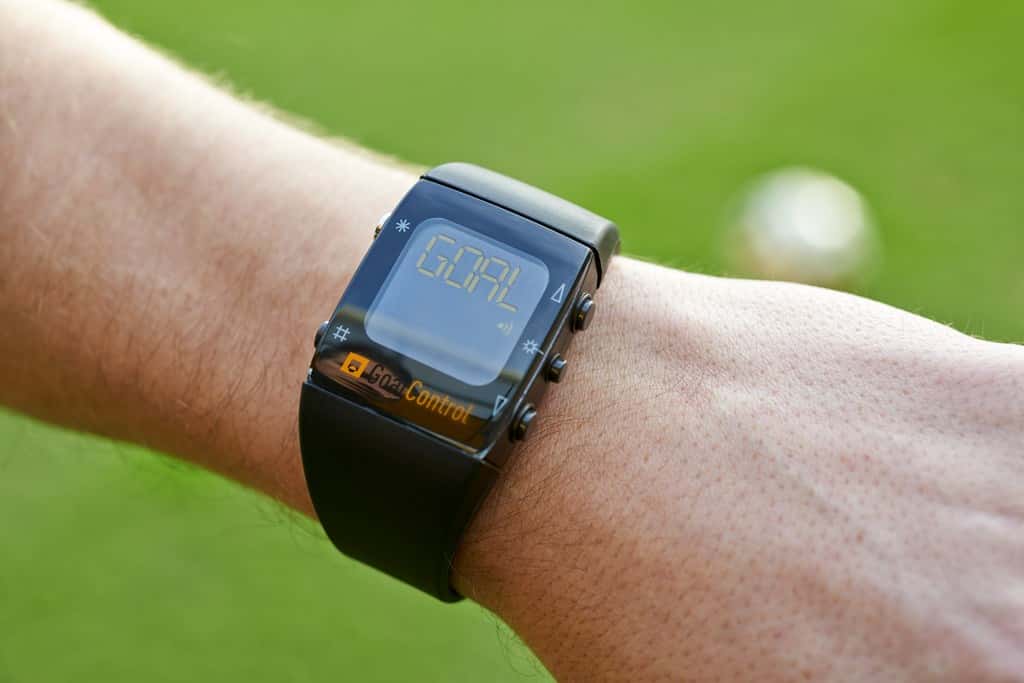 Avec Goal-line, l’arbitre porte une montre connectée avec le système d’analyse GoalControl-4D. Si le ballon passe la ligne de but, un signal radio protégé par chiffrement est envoyé depuis les serveurs. La montre émet une vibration et affiche le mot<em>« goal »</em> sur l’écran pour confirmer le but. © GoalControl