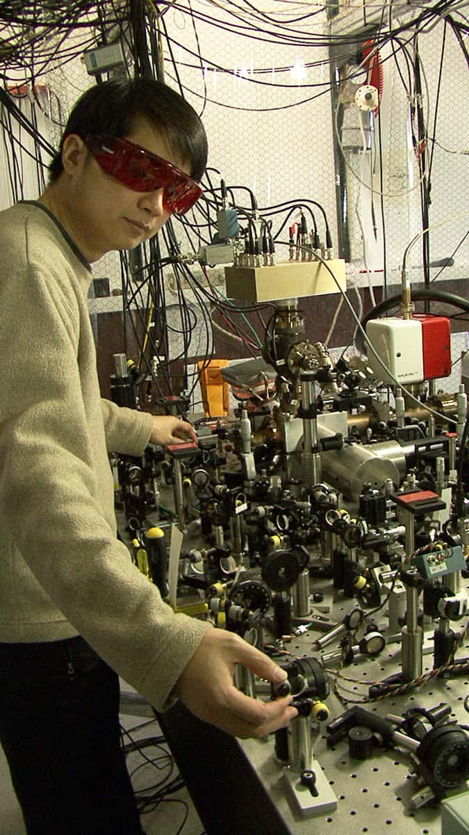 James Chin-Wen Chou, du NIST, devant l'horloge atomique la plus précise au monde, basée sur les vibrations d'un seul ion aluminium. L'ion est piégé à l'intérieur du cylindre métallique (centre droit). © J. Burrus/NIST