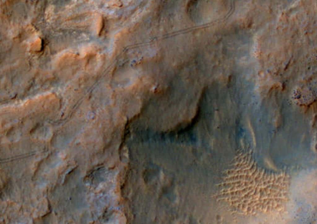 La caméra HiRise, installée sur l'orbiteur MRO (<em>Mars Reconnaissance Orbiter</em>) a saisi le 6 janvier 2014 les traces qu'ont laissées les roues du rover Curiosity, alors en route vers le pied du mont Sharp. Ce robot géologue y cherchera des données sur le passé de Mars, lorsque la Planète rouge avait une atmosphère plus humide et plus chaude. © Nasa, JPL, <em>University of Arizona</em>