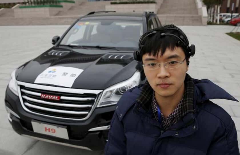 Zhang Zhao, étudiant de l’université de Tianjin, en Chine, a travaillé sur ce projet de conduite via une interface neuronale. Il pose ici avec son casque, devant la voiture équipée du dispositif. © Kim Kyung, Reuters