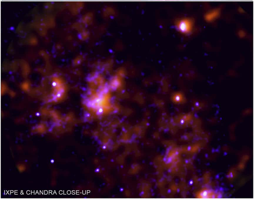 De nouvelles données de l’<em>Imaging X-ray Polarimetry Explorer</em> (IXPE) ont fourni la preuve que Sagittarius A*, le trou noir supermassif au centre de la Voie lactée, a eu une très forte période d’activité il y a environ 200 ans. Les données IXPE, qui montrent l’écho de cette activité, sont visibles ici en orange. Elles sont combinées avec les données de Chandra, un autre observatoire X de la Nasa, visibles en bleu, qui ne montrent que la lumière directe du centre galactique. © Nasa, CXC, SAO, IXPE