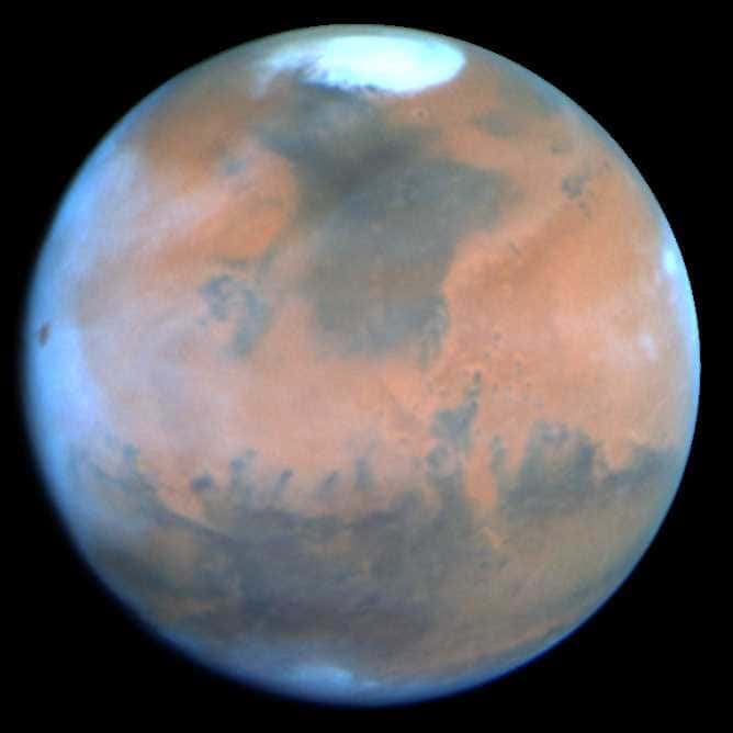 La planète Mars vue par le télescope Hubble en 1995. Cette image d'une exceptionnelle qualité ne nous montre ni visage ni canaux, mais la calotte polaire nord ainsi que de très nombreuses formations. Des nuages matinaux sont visibles sur le bord gauche. Crédit Nasa, Philip James, Université de Toledo; Steven Lee, Université du Colorado