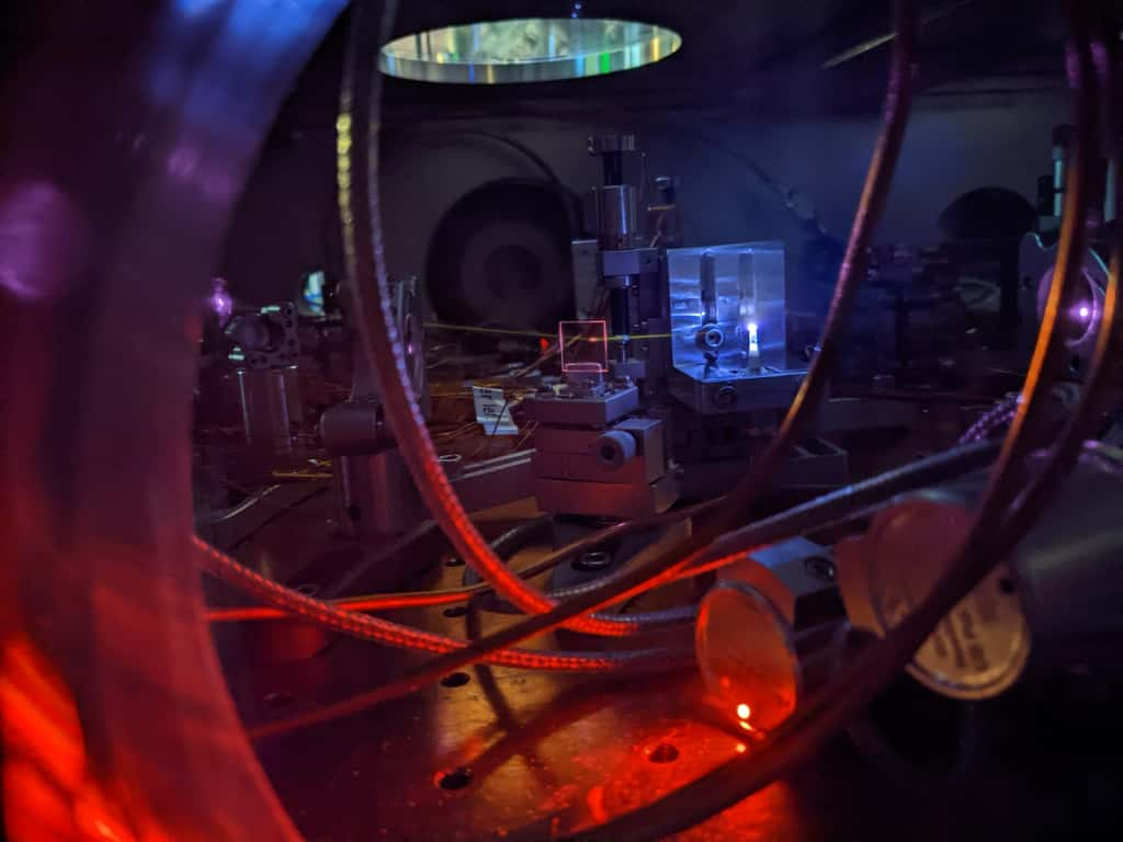 Un puissant faisceau laser traverse un gaz, créant un plasma et générant une lumière ultraviolette. La lumière laisse une ligne blanche visible lorsqu’elle interagit avec le gaz restant dans la chambre à vide. Ce processus aide les scientifiques à mesurer précisément l’énergie nécessaire pour exciter le noyau de thorium 229, qui est le cœur d’une future horloge nucléaire. © Chuankun Zhang, JILA