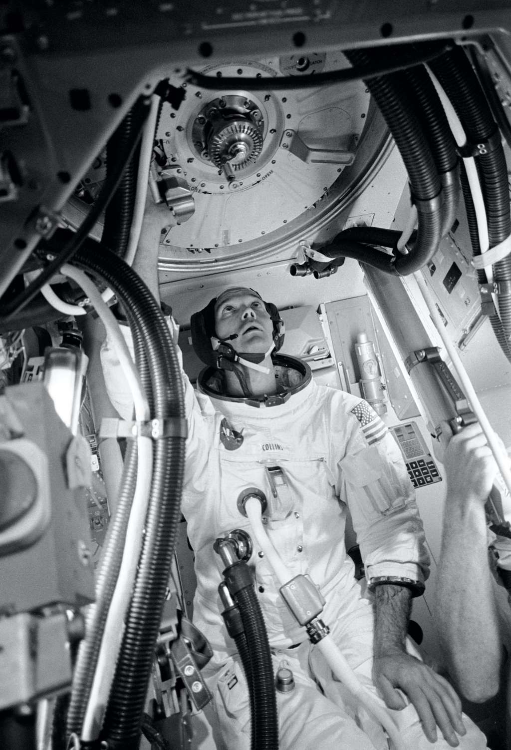 L’astronaute Michael Collins, pilote du module de commande du vol Apollo 11, à l’intérieur d’une maquette de ce module, pratiquant les procédures avec le mécanisme d’amarrage. Michael Collins se tient dans le tunnel d’amarrage qui fournit un passage vers et depuis le module lunaire. © Nasa